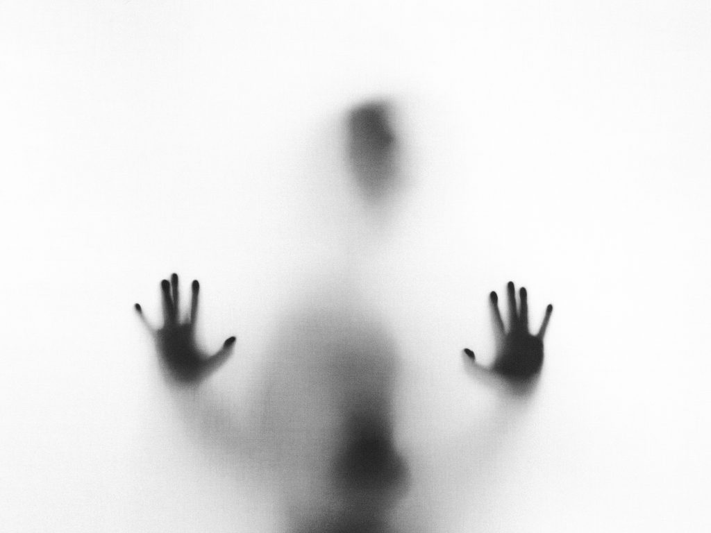 silhouette of a creepy figure behind glass