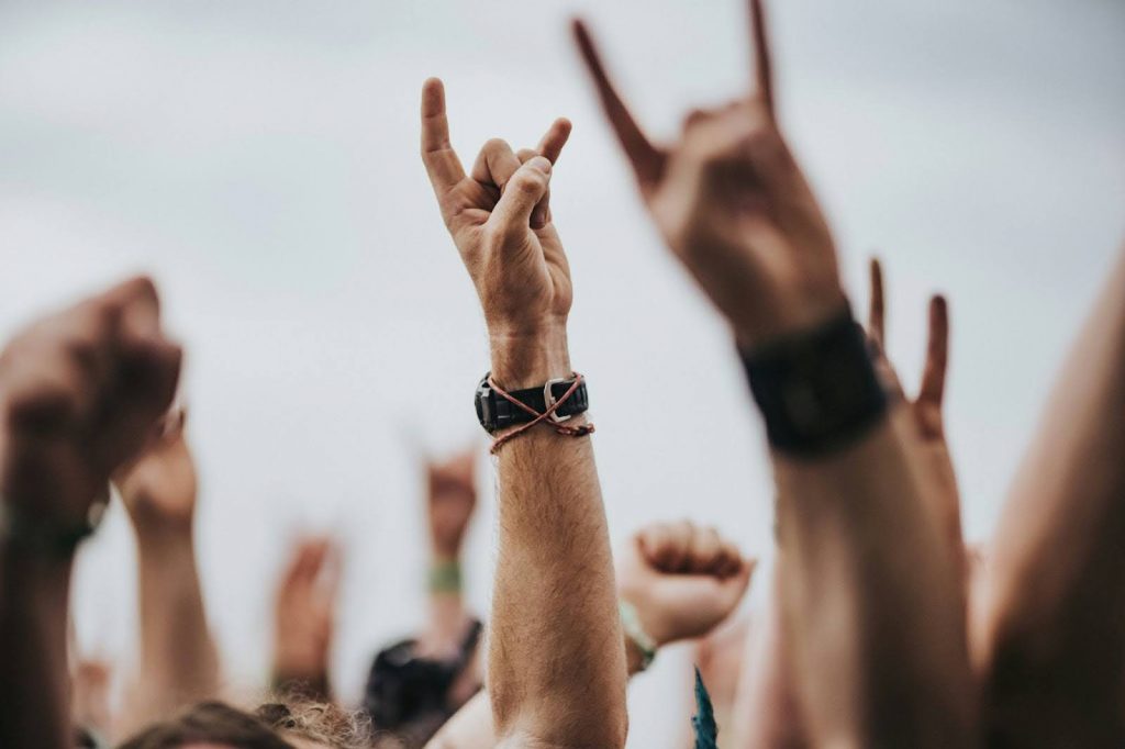 people doing "rock hands" in a festival crowd.